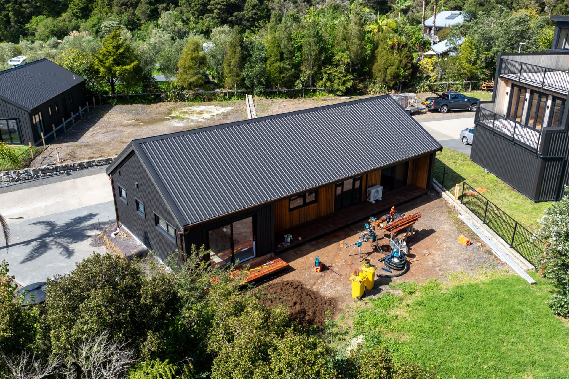 The Tūī — aerial view of the completed dark-clad timber home with cedar accents